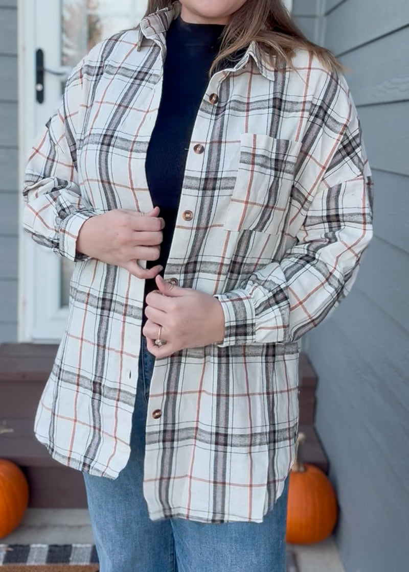 Person wearing a plaid shirt with pumpkins in the background