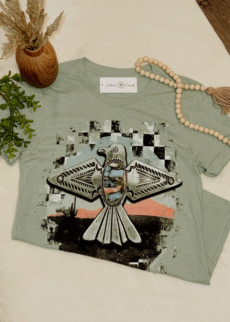 Green t-shirt with a graphic design on a white surface with decorative items.