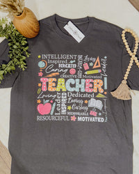 Gray t-shirt with colorful text design on a white surface with decorative items.