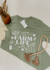 Green t-shirt with 'Farm Life' design on a white surface with decorative elements.